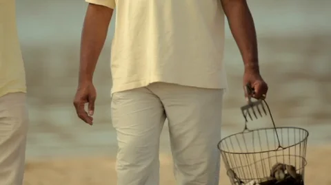 Man walking along the beach with his adult son after collecting shellfish. Video stock 88342924