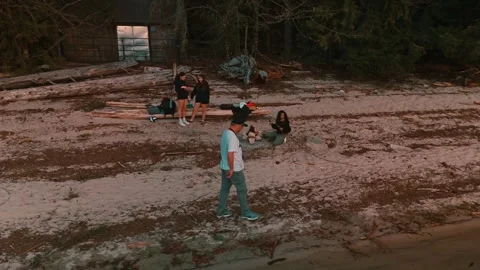 Man walking along beach past group of young ladies enjoying campfire panning Stock-Footage 334248554