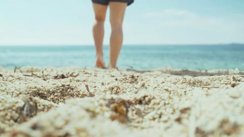 Man is walking along the beach. Young man in a white T-shirt, black shorts and a Stock Footage 154821510