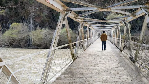 Man walking along the bridge. Forward spring. Rough river. Stock Footage 254670019