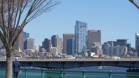 Man Walking Along Charles River with Boston Cityscape in Background Stock Footage 92184110