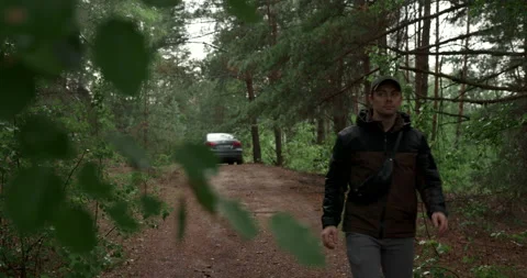 Man walking along dirt path in green forest with car on background Stock Footage 340845647