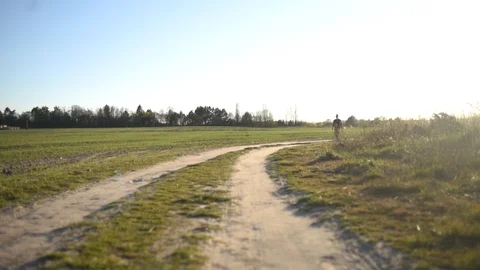 Man walking along a path in a green field Stock Footage 128987226