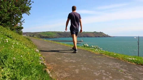 Man walking along path, ocean in background Stock Footage 49325597