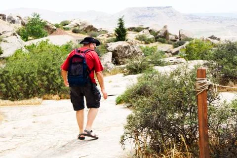 Man is walking along the road with a backpack on his back. Sunny sunset Stock Photos