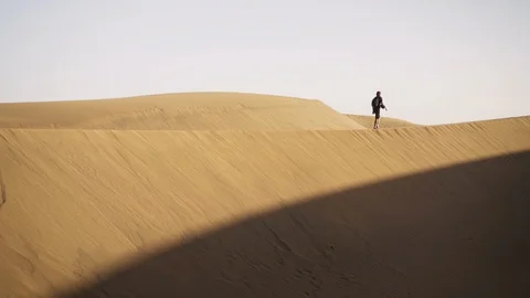 Man Walking Along Sand Dune In Desert Stock Footage 129663094