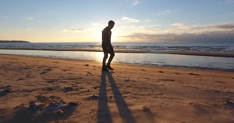 Man walking along sandy beach at sunset. 動画素材 99008061