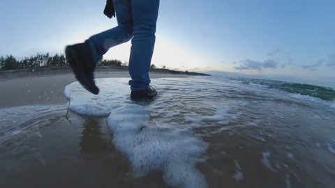 Man Walking Along Sandy Beach Low Tracking Shot at Sunset Video stock 125007537