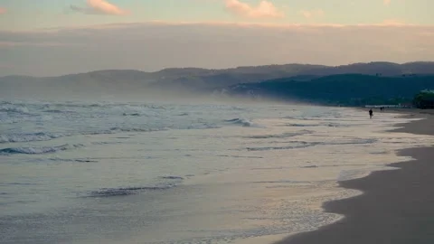 Man walking along sandy shore Stock Footage 221581829