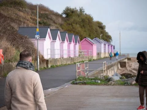 Man Walking along Seafront with colourful beach huts Stock Photos