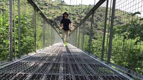 Man is walking along the suspension bridge of Khndzoresk, Armenia Stock Footage