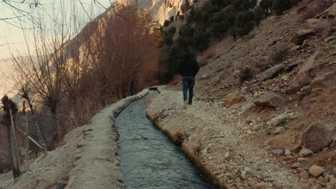 A man walking alongside of a small river stream in the mountains Stock Footage 169837920