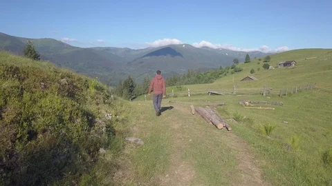 Man walking on the alpine green grass mountain field Stock Footage 78420027