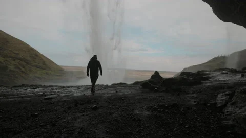 Man Walking and enjoying Inside The Cave In Seljalandsfoss Waterfall In Iceland Stock Footage 178555078