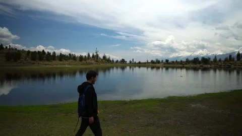 A man walking and looking at the Radian lagoon surrounded by several snow-capped Vidéo 164597337