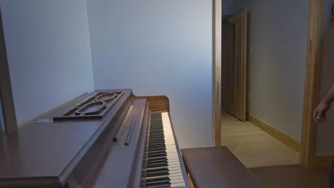 Man walking in and sitting down to play the piano Stock Footage 122184478