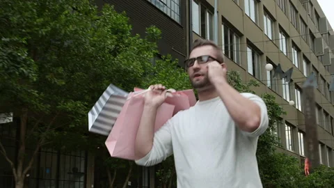 Man walking and talking on smartphone with shopping bags in the city Stock Footage 199632091