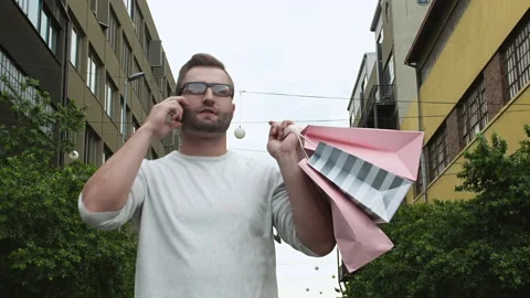Man walking and talking on smartphone with shopping bags in the city 스톡 동영상 199632095