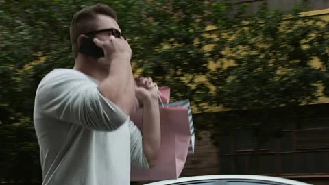 Man walking and talking on smartphone with shopping bags in the city. Steadicam Video stock 199632330