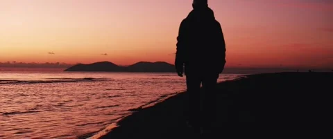 Man walking away along the beach at sunset Video stock 324461389