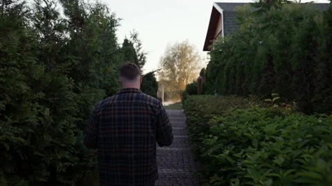 Man walking away through green shrubs at dusk Video stock 203791983