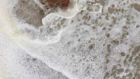 Man walking bare foot on sandy beach into ocean wave, point of view. Stock Footage 75825892