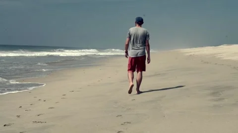 Man walking barefoot and alone on a desert beach Stock Footage 45480192