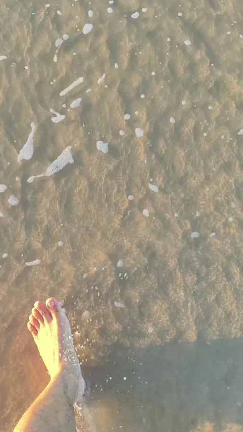 Man walking barefoot on sandy beach at sunset POV Stock Footage 340381263