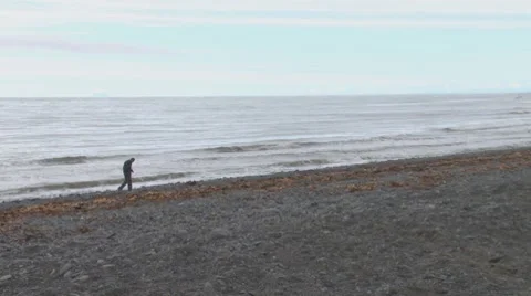 Man Walking on Beach Alone Under Gray Skies Stock Footage 8558090