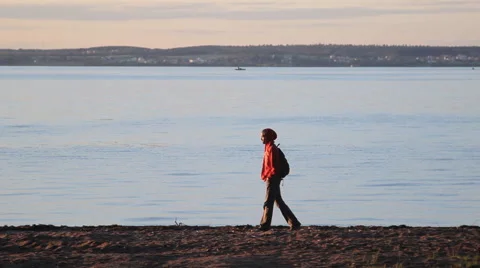 Man walking on the beach along the lake at sunset 動画素材 65220193