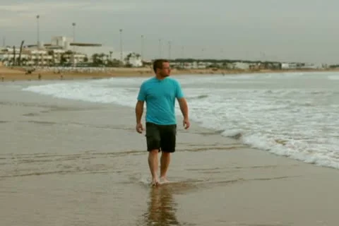 Man walking on beach and looking at the sea, slow motion Stockbeeldmateriaal 10791540