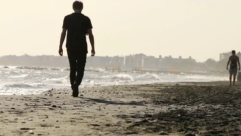Man walking on the beach and seeing on the sea Stock Footage 98939623