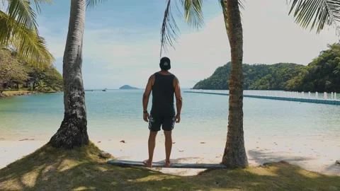 Man walking on a beach and standing near coconut trees Stock Footage 232910512
