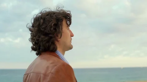 Man walking on the beach and talking on cellphone, steadycam shot Video stock 72749990