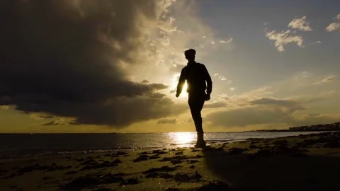 Man walking on the beach, beautiful sunset on the sea. Slow motion. Stock Footage 80307362