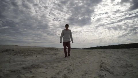 Man walking on beach on cloudy day Stock Footage
