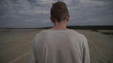 Man walking on beach on cloudy day Stock Footage