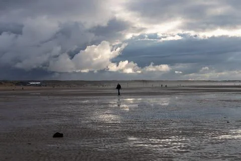 Man walking on the beach on a cloudy day Stock Photos