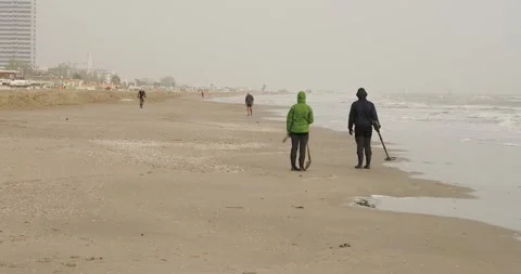 Man is walking on the beach holding detector finding metal in the sand Stock Footage 270467359