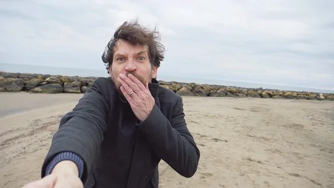 Man walking on beach holding hand of girlfriend blowing kiss Stock Footage 85528558