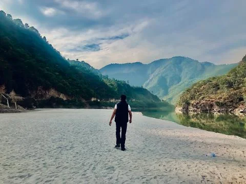 A man is walking on the beach near mountains in Uttarakhand India Stock Photos