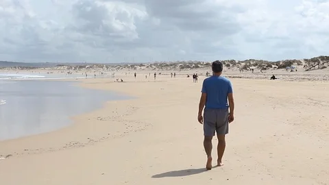 Man walking on beach on sand Video stock 125464990
