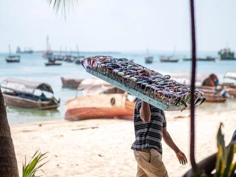 Man walking on the beach with sea in background selling sunglasses. Foto stock