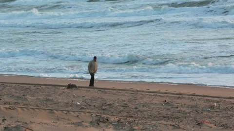 Man walking on the beach with storm waves at sunset Stock Footage 35251761