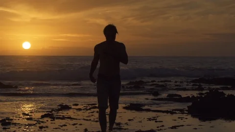Man walking on beach at sunset Stock Footage 85817901
