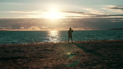 Man walking on the beach at sunset Stock Footage 200827257