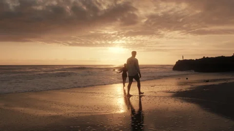 A man walking on the beach at sunset Stock Footage 269257881