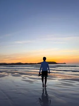 Man walking on the beach at sunset Stock Photos
