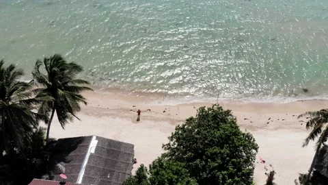 Man Walking in Beach Town with Ocean and Mountain in the Horizon in Thailand Stock Footage 142314633