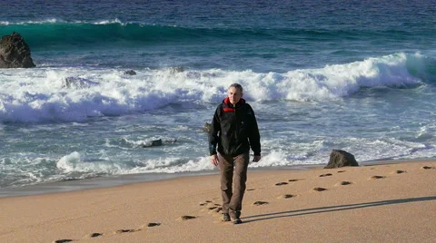 Man Walking on Beach with Waves in the Background Stock Footage 45701794